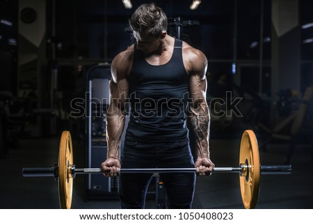 Handsome young fit muscular caucasian man of model appearance workout training in the gym gaining weight pumping up muscles and poses fitness and bodybuilding sport concept