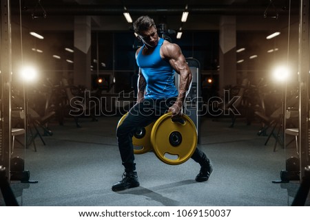 Handsome young fit muscular caucasian man of model appearance workout training in the gym gaining weight pumping up muscles and poses fitness and bodybuilding sport concept