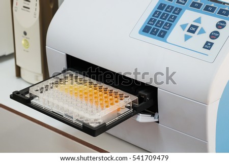 Scientist is putting ELISA plate to measure OD with micro plate reader, Selective Focus