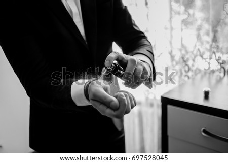 The groom is holding perfume. groom have a final preparation for wedding - man holing a parfume bottle and spraying fragrance on hand