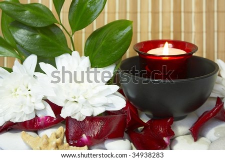 Spa candle with rose petals, white flowers and stones
