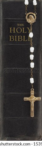 Rosary over spine of an old Bible.