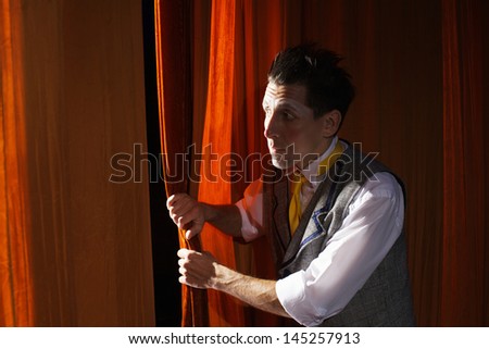 The clown is peeking through the curtain,before his act