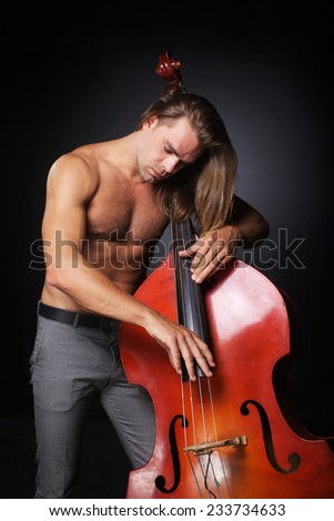 The handsome man with long hair and naked torso is hold double-bass