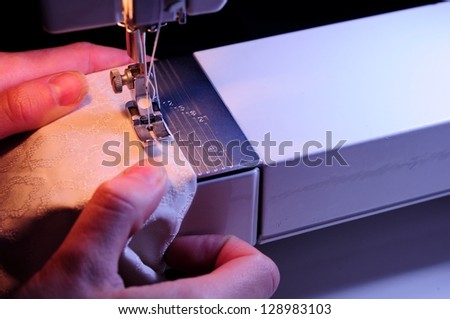 A seamstress sewing white fabric on a sewing machine
