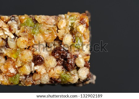 A close-up of muesli (granola) bar with puffed rice, raisins, honey and sugared fruits