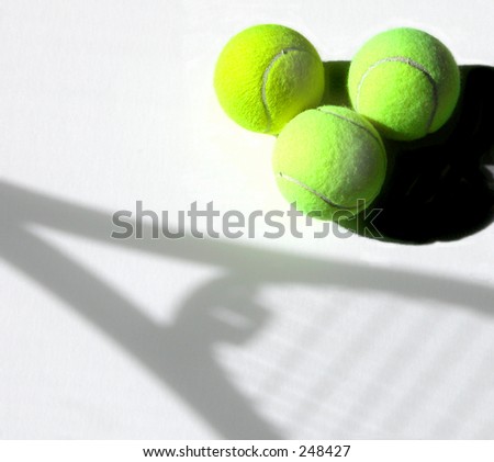 Three tennis balls next to a shadow of a tennis racquet