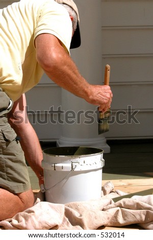 Rear view of man on knee brushing on deck stain
