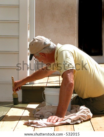 Close up shot of man on knee brushing on deck stain