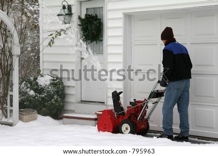 Man using a snow blower to clear out a driveway