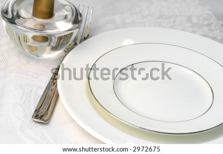 Table set for dinner with a white plate and table cloth (blur added to soften details)