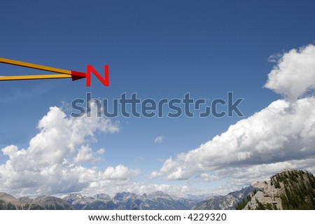 N for North. A red letter for the direction its pointing.  Beautiful blue sky with clouds in the background.  There several in this series for the 4 directions (North, South, East, and West)