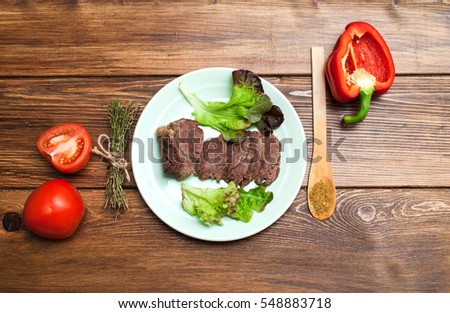 boiled beef with vegetables, tomatoes and pepper on a wooden background . Kind of hot dishes on top.