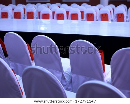 chairs in white covers in the hall for a fashion show gift bag on a white chair
