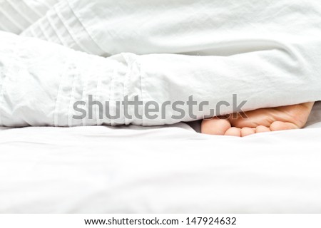 Sleeping person\'s foot out of the white blacket