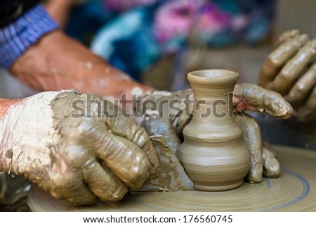Old Man Teaching Young Woman How To Work On Pottery Wheel