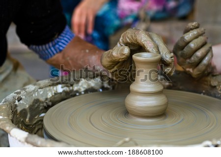 Old man teaching young woman how to work on pottery wheel