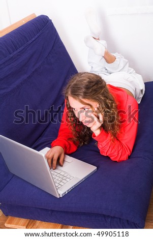 Nice girl works on laptop lying on the sofa
