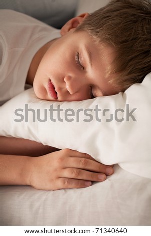 Cute boy sleeping on white pillow