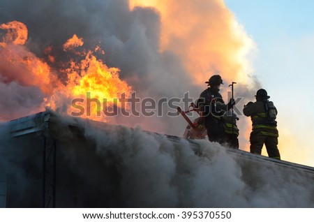 Firefighters on the roof of a house that is on fire
