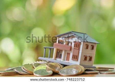 A model house model is placed on a pile of coins.as background real estate concept with copy space.