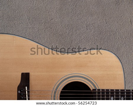 Color photo of an acoustic guitar near wall