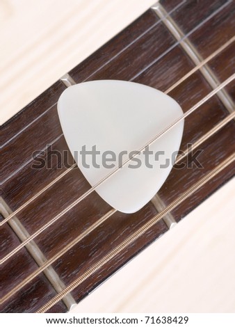 Color photo of acoustic guitar and pick on wood
