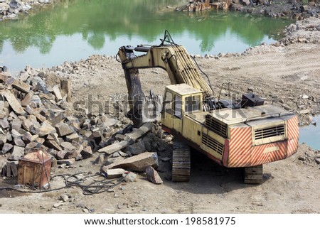 Track-type loader excavator machine doing earth-moving work at basalt quarry
