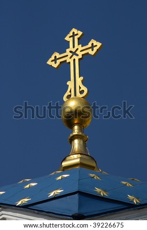 Gold cross and gold stars on dome over blue sky