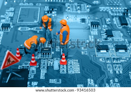 Miniature engineers fixing error on chip of circuit board. Focus on word \