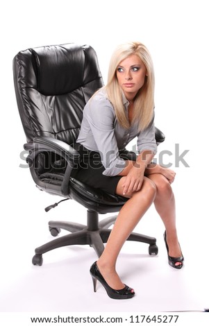A thinking business woman sitting facing front in a black knee length skirt and high heels isolated on white.