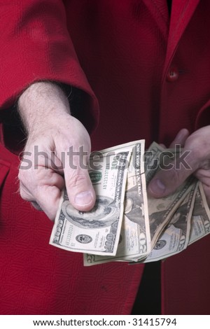 A man in a red sport  coat handing money to someone in the vertical format.