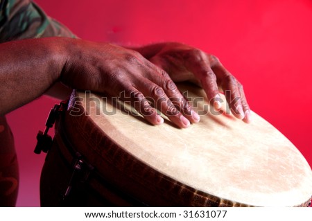 An African or Latin Djembe being played against a red background in the horizontal format.