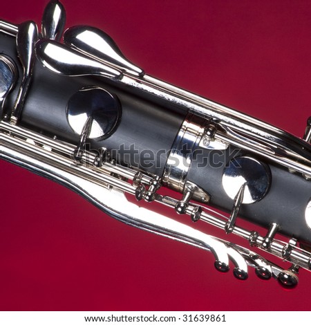Bass clarinet keys isolated against red background in the square format with copy space.