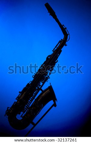 A saxophone in silhouette against a blue background in the vertical  format with copy space.