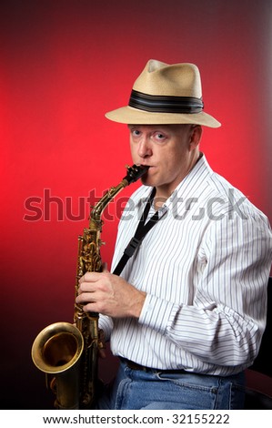 A professional saxophone performer and hat isolated against a red background in the vertical format with copy space.