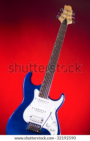 A blue electric guitar isolated against a red spotlight background in the vertical format.