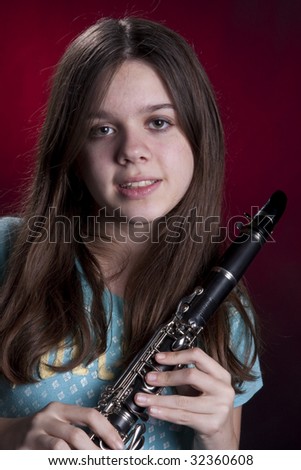 A teenage girl clarinet player isolated against a dark red background in the vertical format.