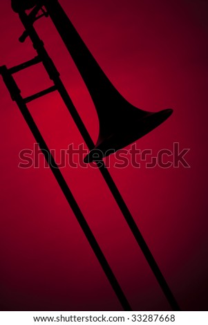 A trombone silhouette isolated against a red spotlight background in the vertical format.