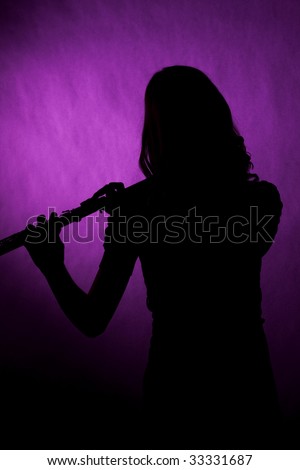 A teenage girl female flute player isolated in silhouette against a dark pink background.