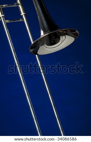 A gold brass and silver trombone isolated against a dark blue background in the vertical format.