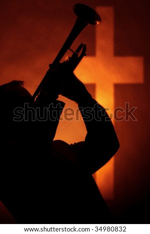 A trumpet player musician in silhouette before a gold cross in the vertical format.
