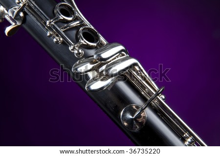 A soprano clarinet isolated against a purple spotlight background in the vertical format.