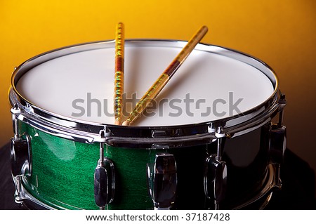A green snare drum isolated against a gold background in the horizontal format with copy space.