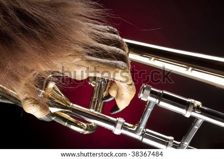 A Halloween holiday gold brass trombone with a monster?s hand against a red and black background in the horizontal format.