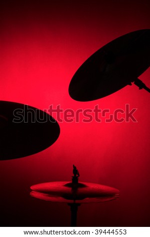 A set of drum cymbals in silhouette isolated against a red background in the vertical format with copy space.