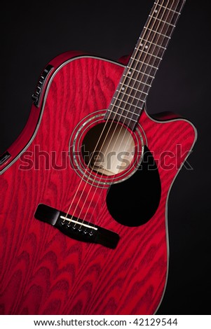 A red acoustic electric guitar isolated against a black background in the vertical format.