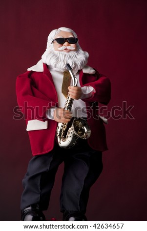 A toy Santa Clause with dark glasses playing saxophone isolated against red background.