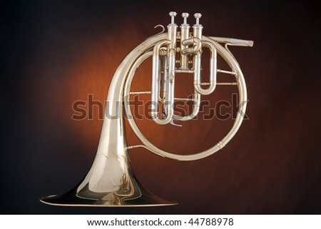 A gold antique peck-horn or French horn isolated against a spotlight gold background.