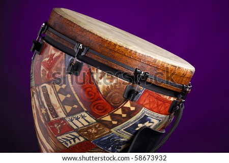 An African Latin djembe or conga drum isolated against a spotlight purple background.